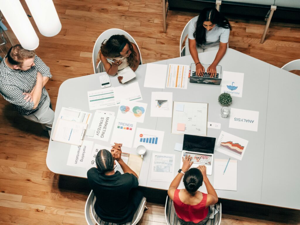 The Benefits of Partnering with the best SEO Services agency in bangalore in 2025. A diverse group working on marketing strategies with charts and laptops in an office setting.